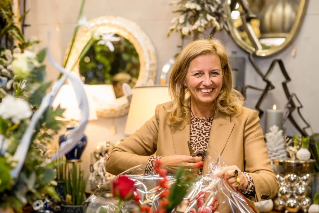 Uśmiechnięta florystka tworzy bukiet i pakuje kwiaty w kwiaciarni – praca przy kompozycjach florystycznych